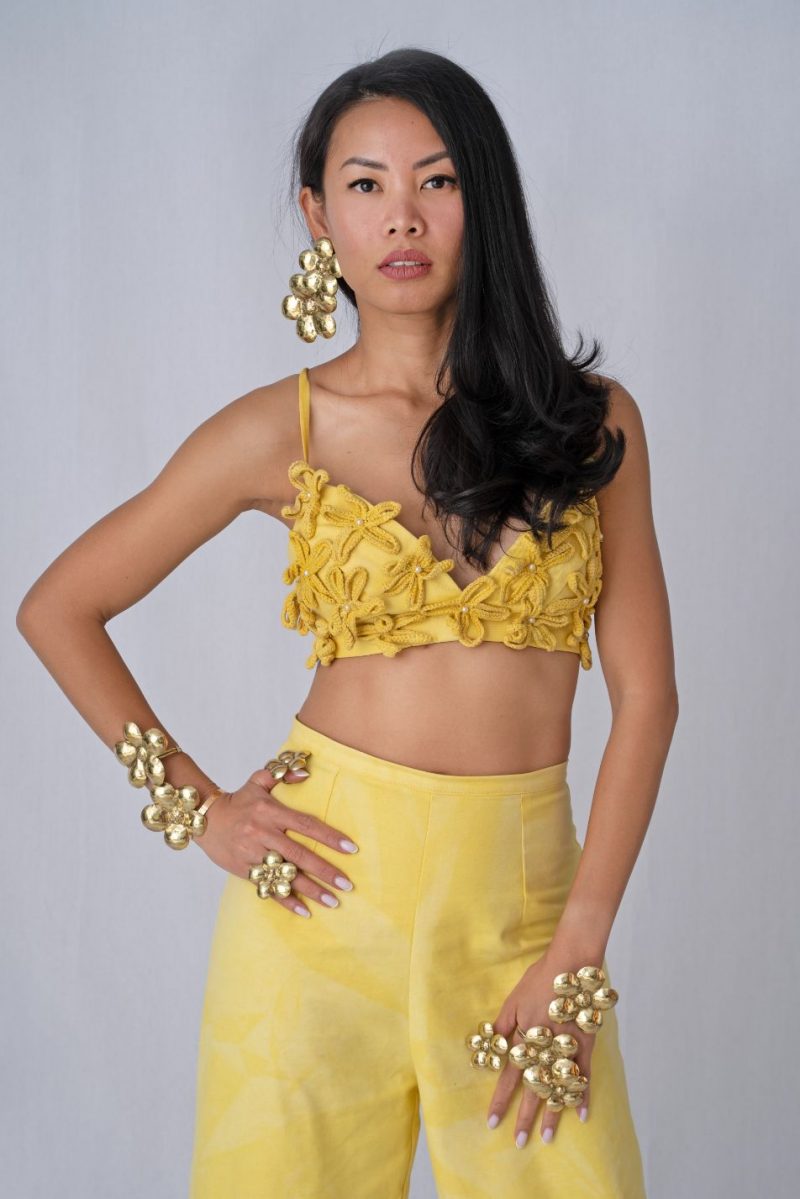 girl wearing yellow crop top and yellow pants with brass jewelry